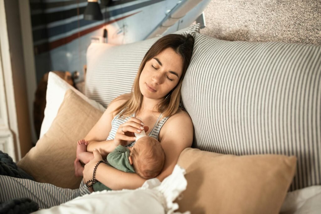 Bebé tomando biberón con supermamá durmiendo en el sofá de bebeleporino.com