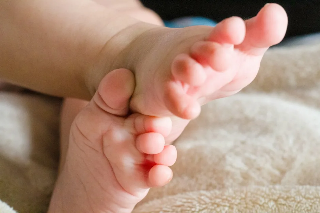 Manos formando un corazón con los pies de un bebé